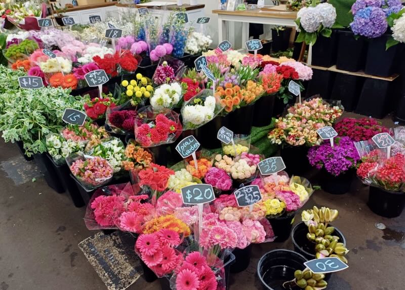 Bouquets of flowers sit in bins at the market.