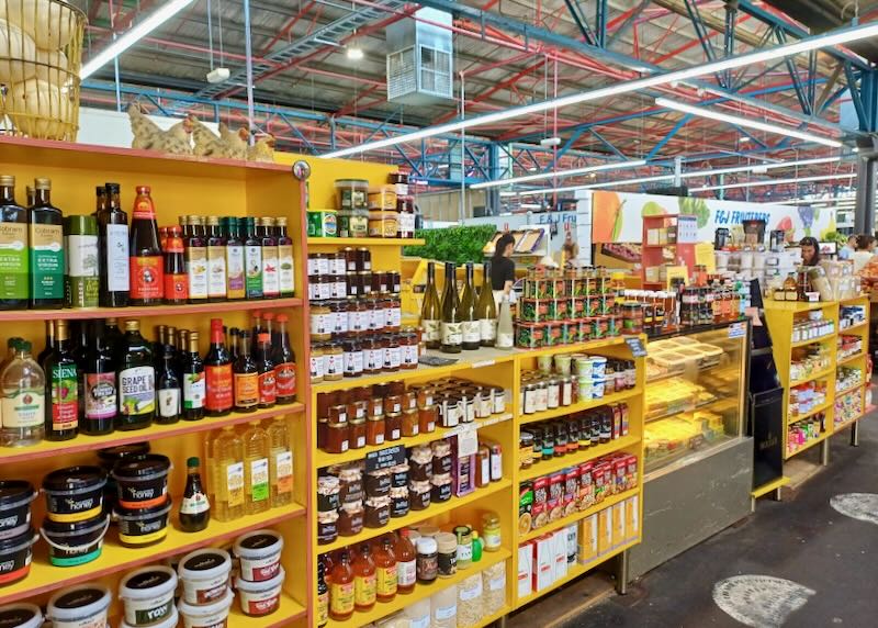 Yellow shelves in a market hold jellies, vinegars, and spreads.