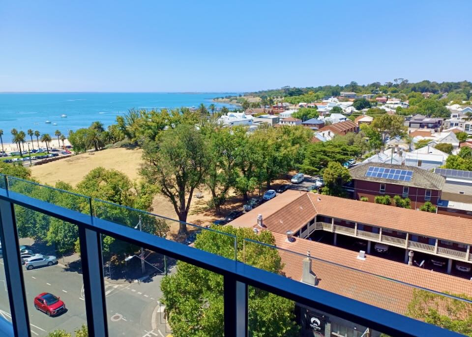 A view of the ocean and roof tops from a balcony.