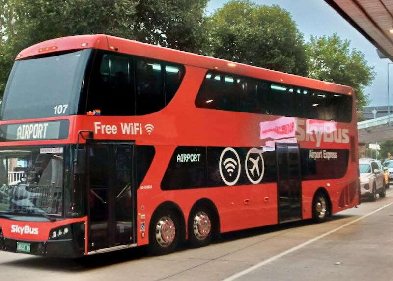 A red bus pulls away from the curb.