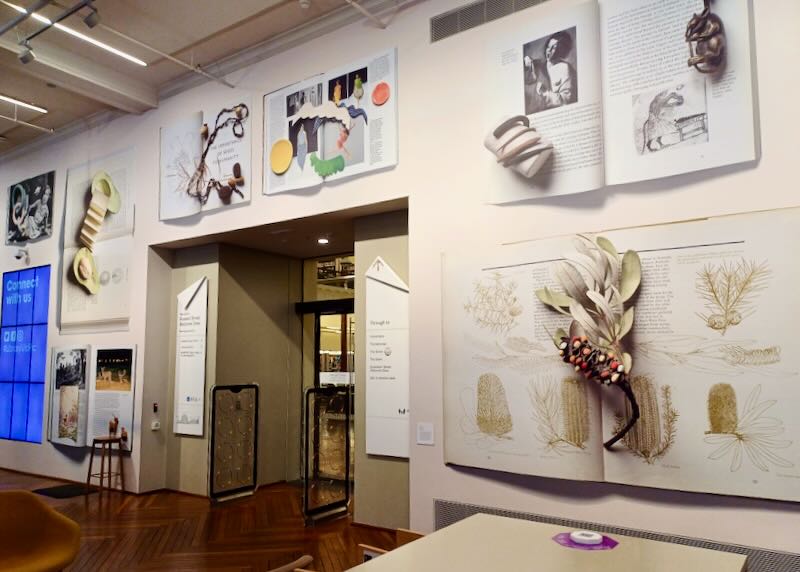 A wall of photographs of open books and three-demential objects on top.