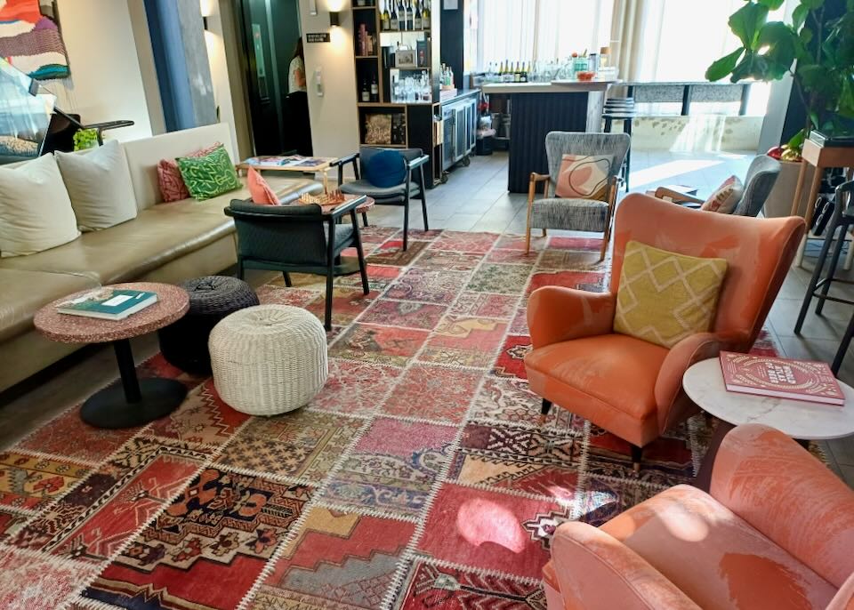 Coral colored chairs sit on a patchwork of old sew-together rugs.