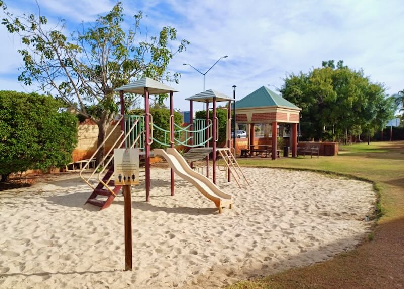 A playground with a slide on sand.