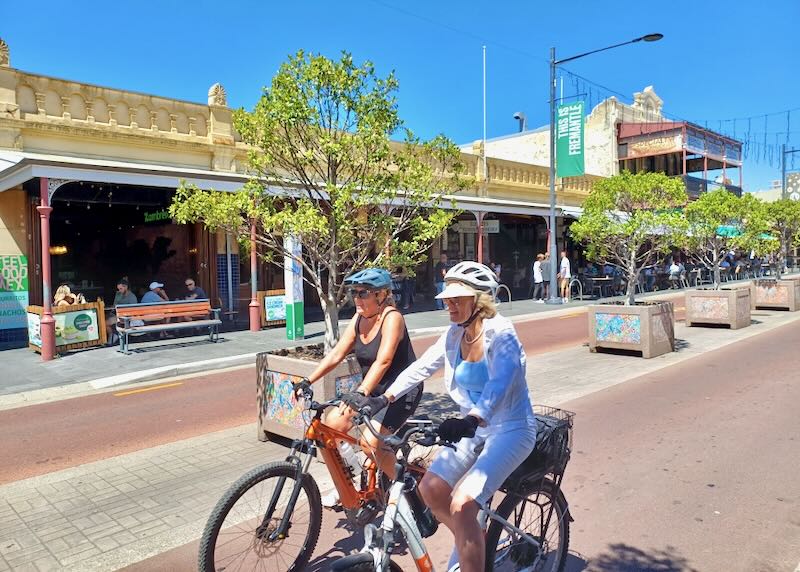 Two women bicycle on a path.