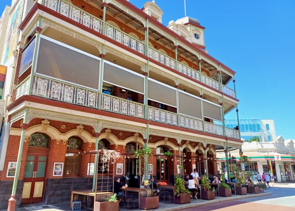 A three-story older brick hotel with white metal railings.