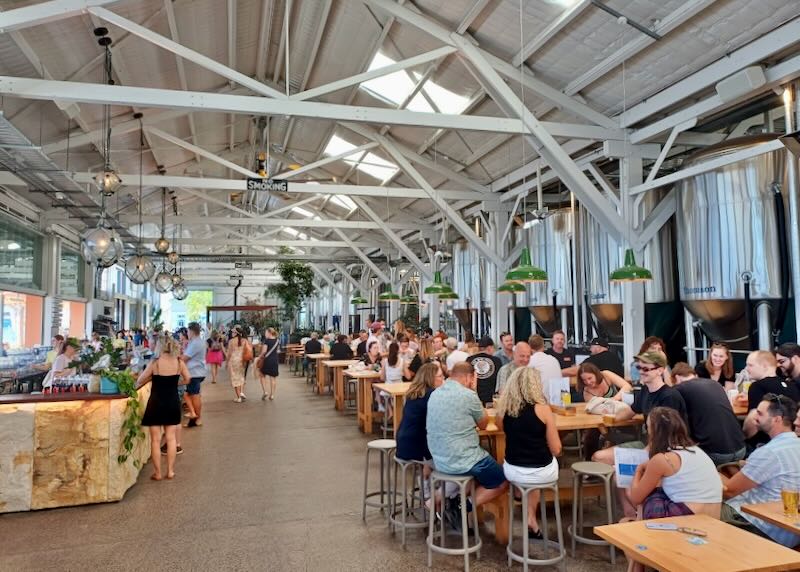 People sit at tables at a restaurant in a large shed.