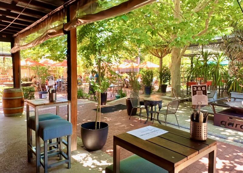 Tables and chairs sit in a garden.