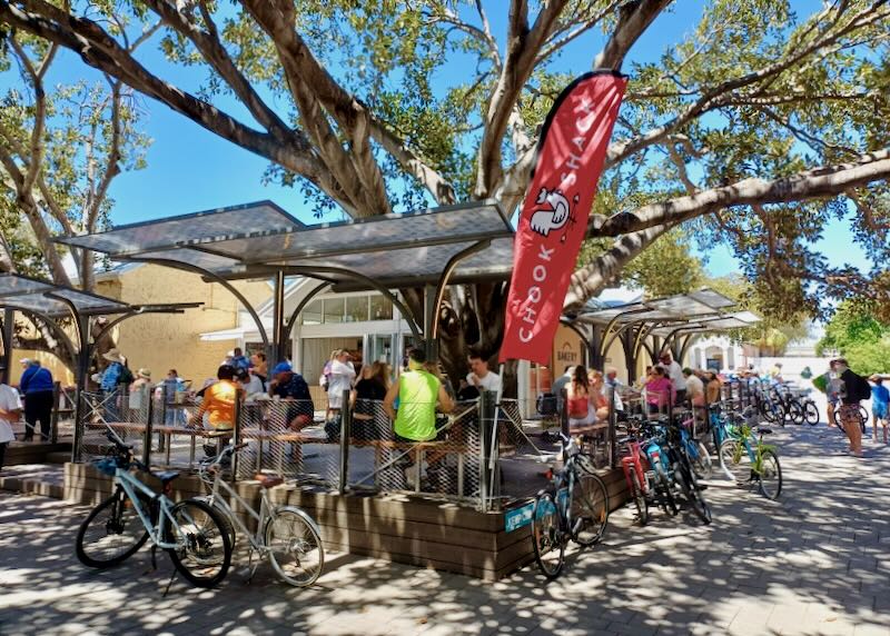 People sit at food tables next to bikes.