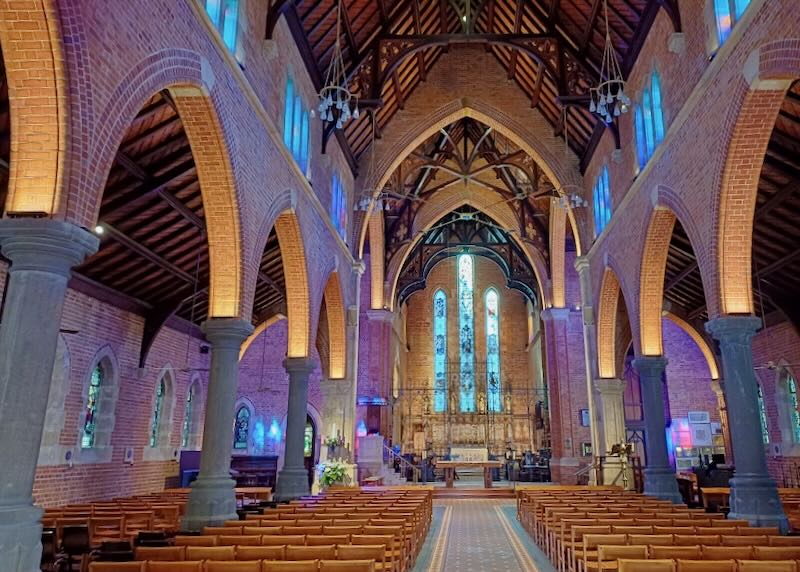 The inside of a tall cathedral with wooden buttresses.