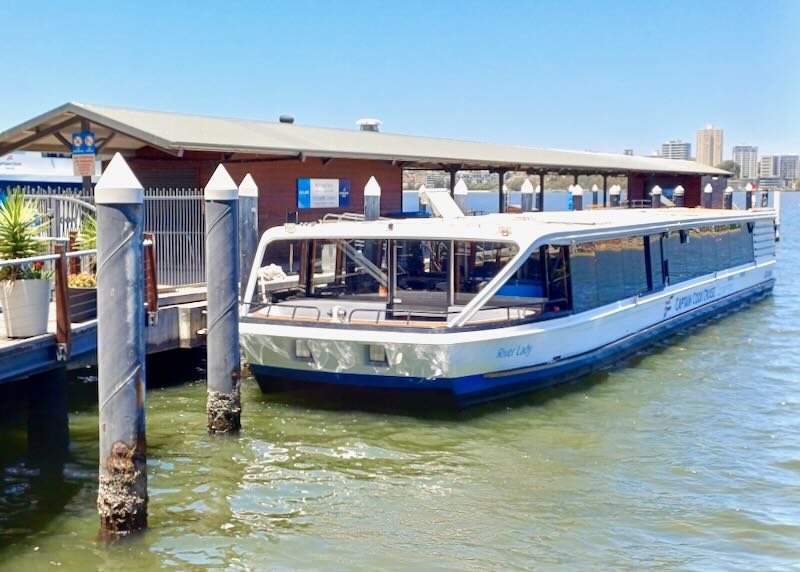 A small flat river cruise boat sits anchored to a dock.