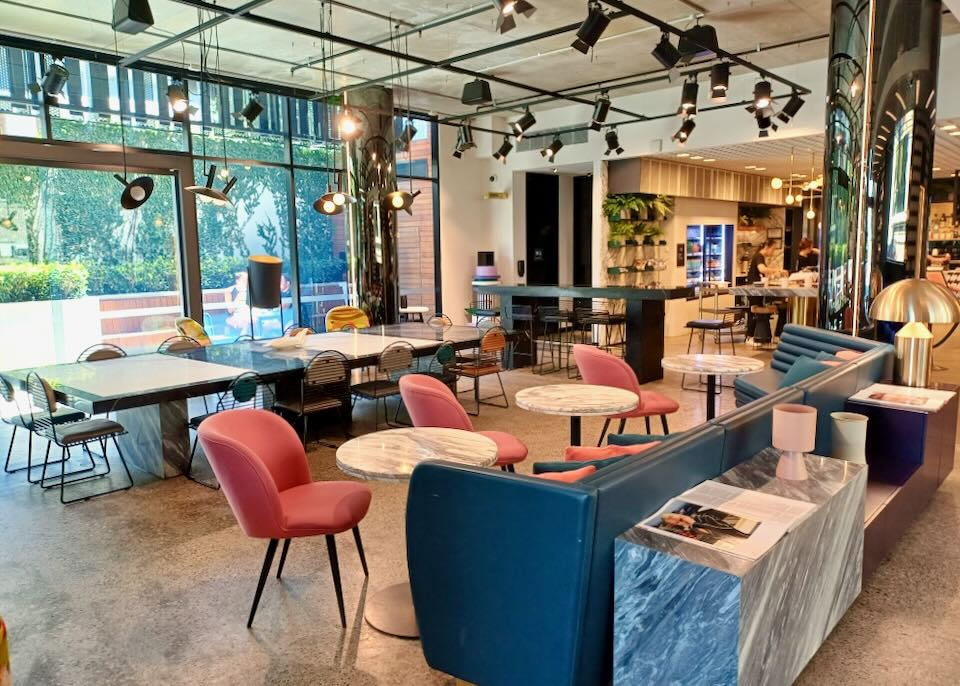 A dining room filled with coral colored chairs and long dark blue booths.