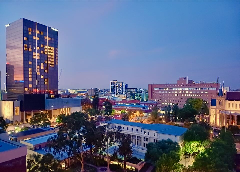 A tall building reflects a purple and blue sky.