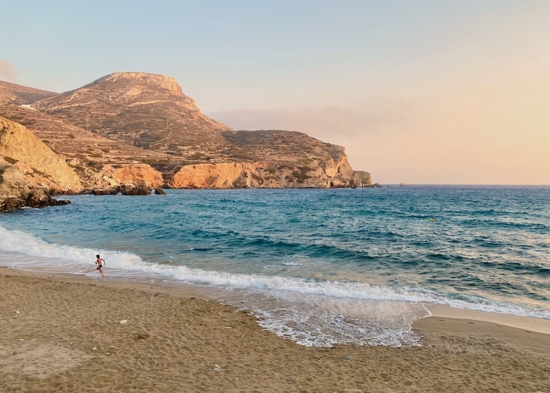 A boy running along a beach near sunset in Agali, Folegandros.