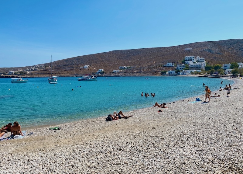 People swimming and sunbathing on a crescent-shaped beach.