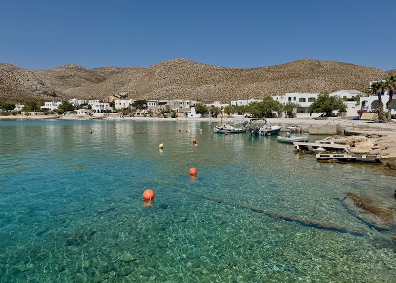 Clear blue water with a few boats and buoys near the beach in Karavostasis, Folegandros.