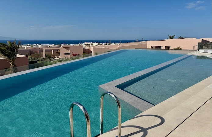 An infinity pool with a shallow section attached facing the Aegean Sea at Domes Novos hotel in Oia, Santorini.