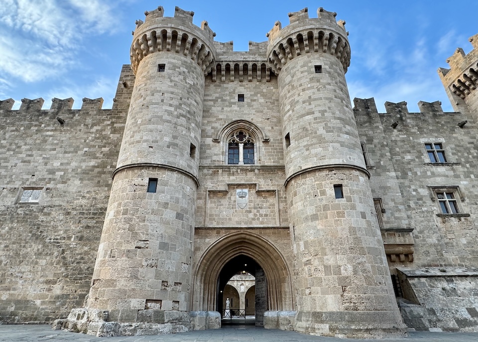 In front of the gatehouse of the medieval stone castle, the Palace of the Grand Master of the Knights of Rhodes with rounded towers and battlements in the Old Town.