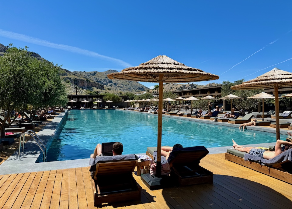 A long pool with sunbed and umbrella sets lining all four sides at Cook's Club in Kolympia, Rhodes.