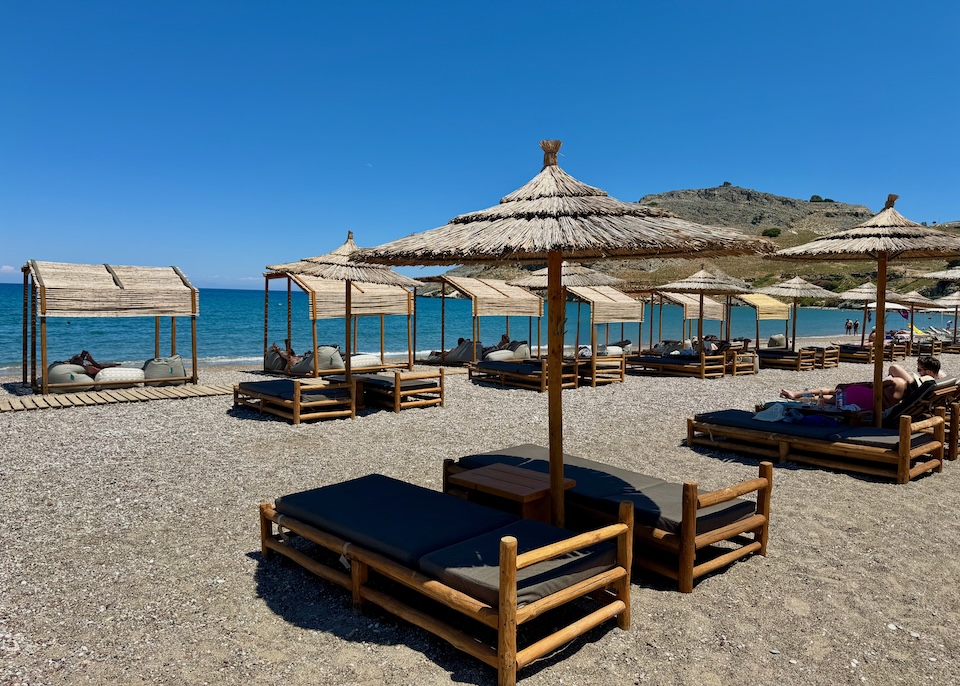 Bamboo cabanas and sunbed-umbrella sets at Lindos Aqua Terra on Vlycha Beach.