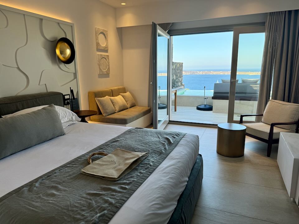 Hotel room with open balcony doors leading out to a private hot tub with ocean views