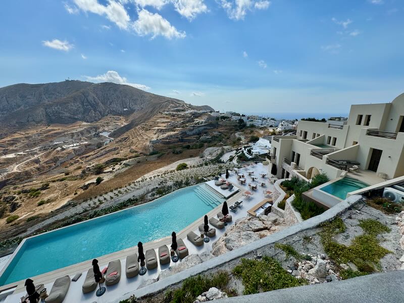 View from above over a hotel complex in Pyrgos village with a sprawling pool deck and outdoor restaurant.