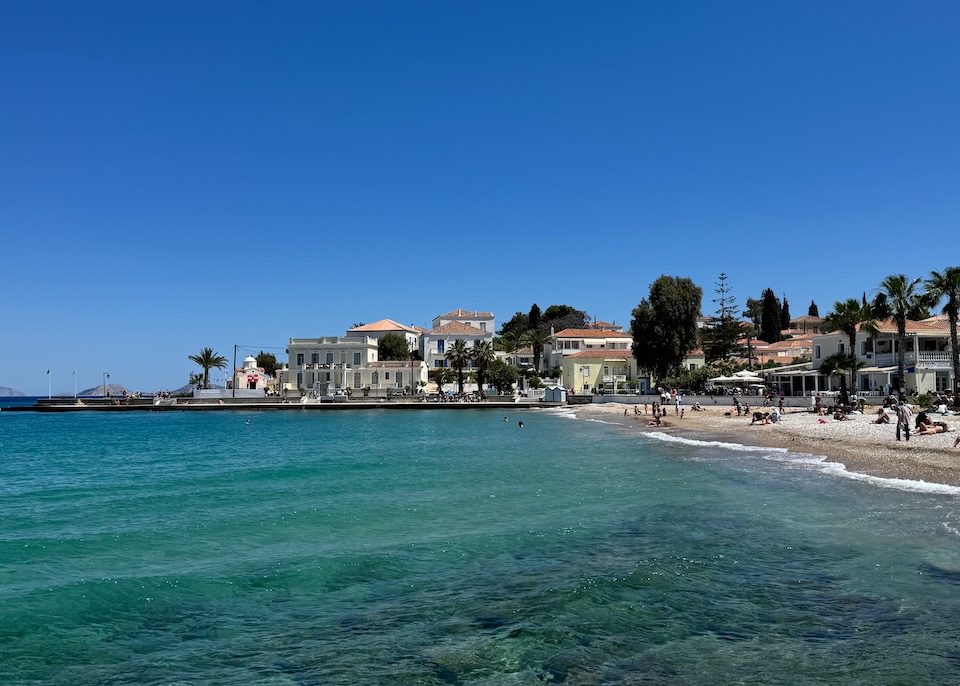 A busy little beach lined with neoclassical buildings in Dapia, Spetses.