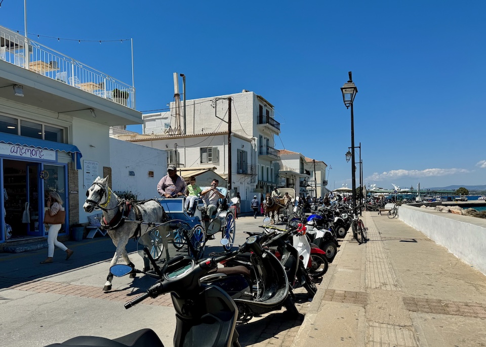 Horsedrawn carriages heading south on the main seafront road in Dapia, Spetses.