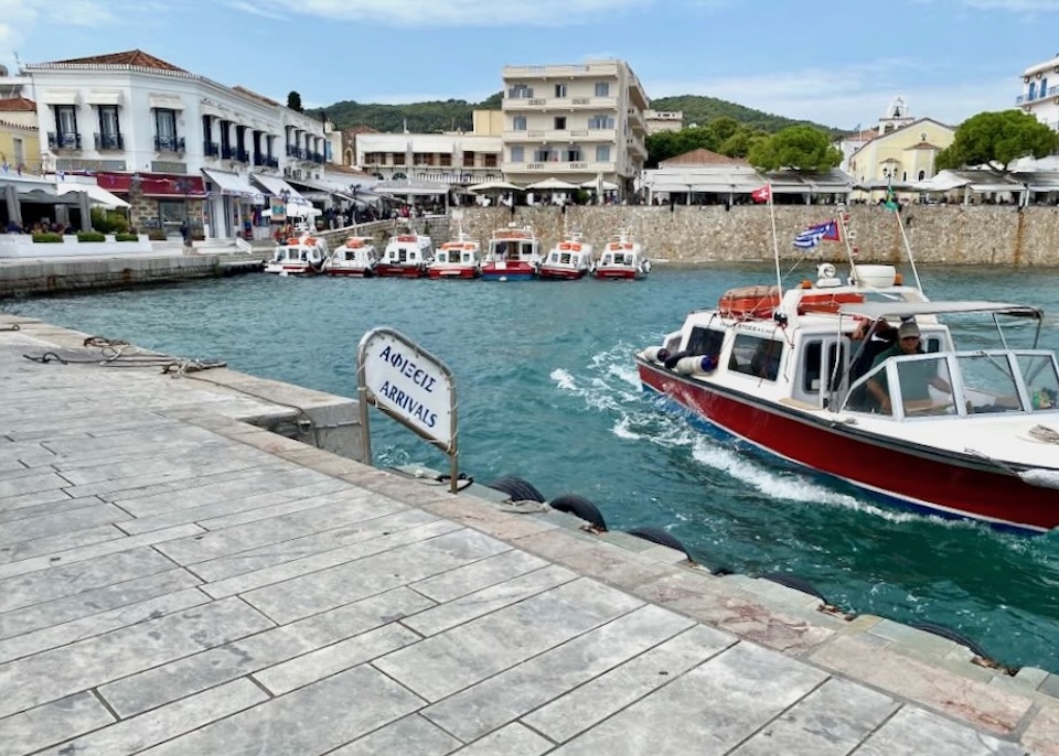 One water taxi arriving at the dick, while a row of taxis are anchored in the background waiting to pick up passengers in Dapia Port.