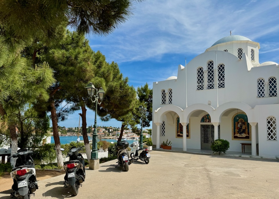 Exterior of a blue-domed Greek Orthodox church on a hilltop overlooking the sea in the Old Harbor of Spetses.