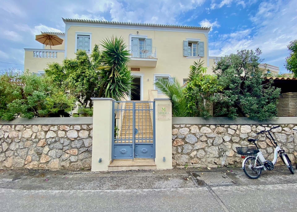 Exterior view of Mimoza hotel and garden behind a stone fence in Spetses.