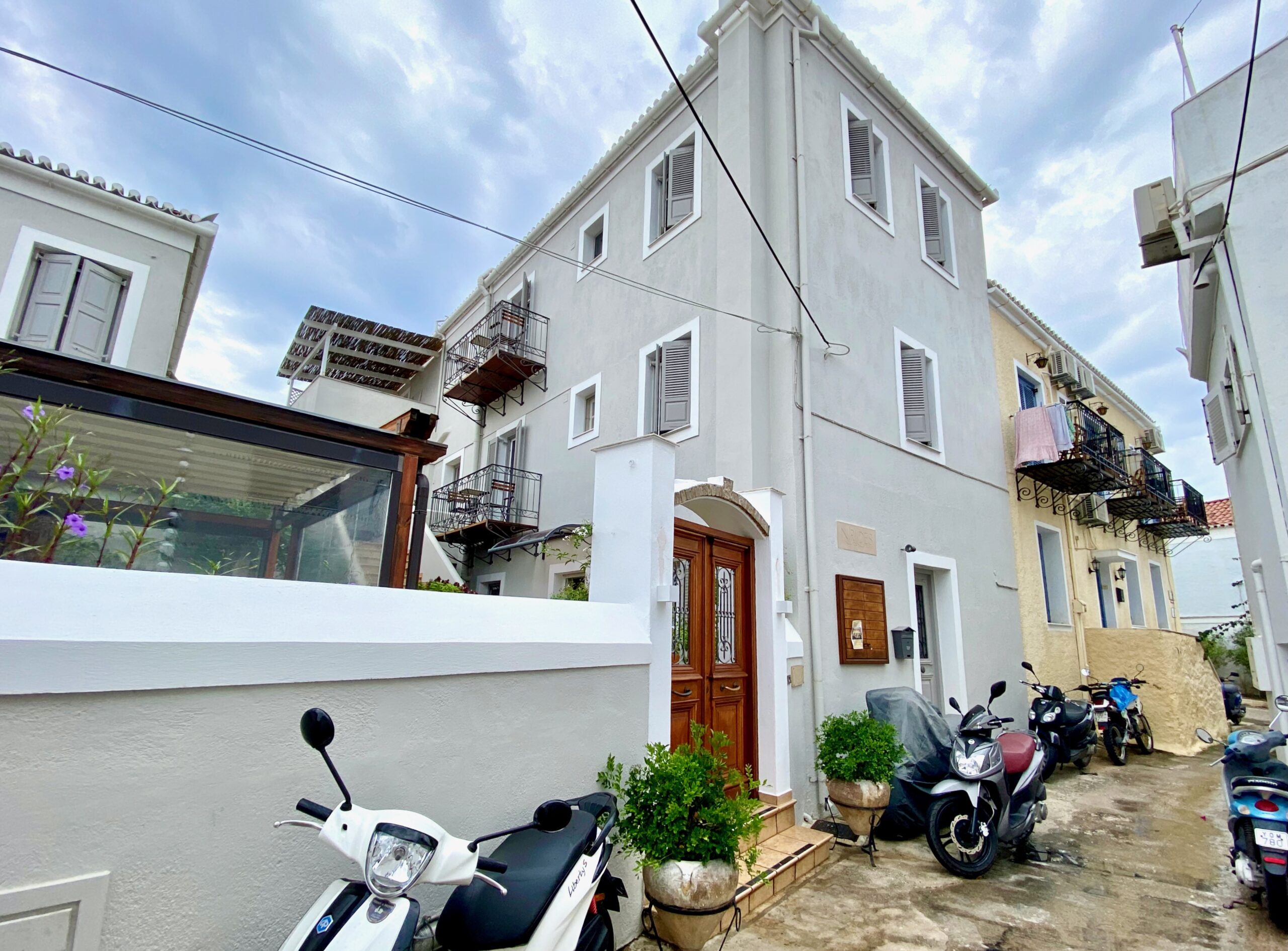 Exterior view of Niirides hotel on a narrow side street with scooters parked in Spetses.