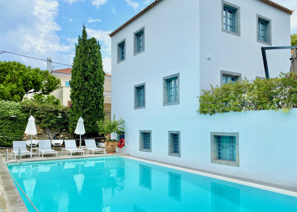 A pool with sunbeds at the far end next to the main building of Orloff Resort in Spetses.