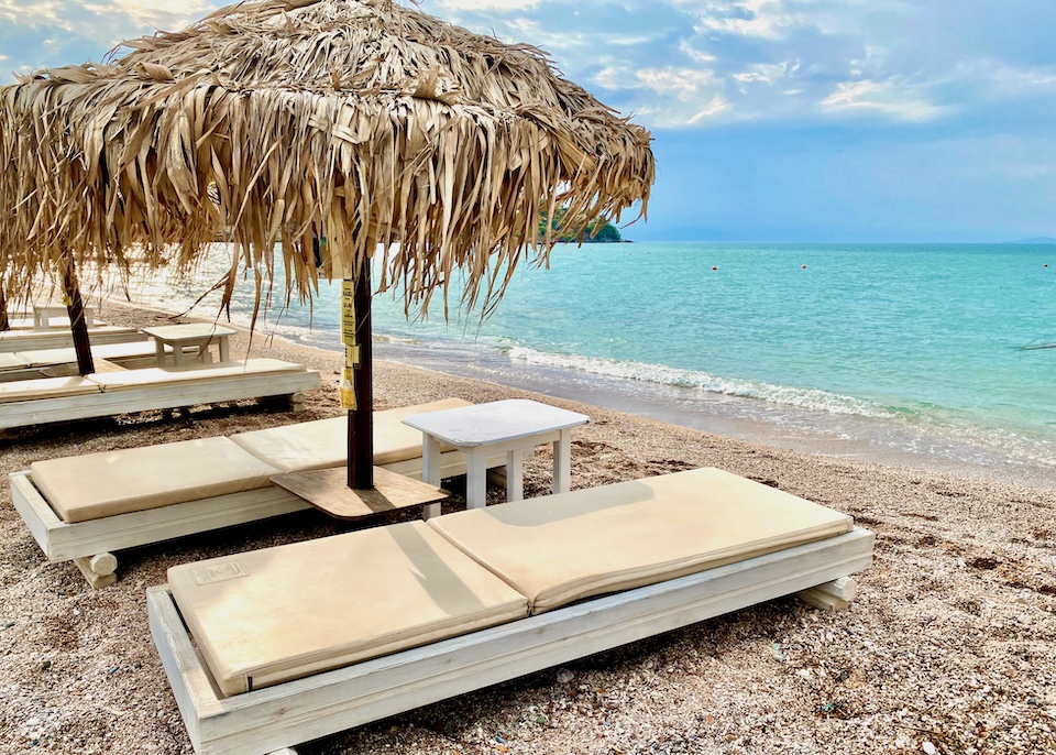 A row of sunbeds and thatched umbrellas on a beach in Kounoupitsa, Spetses.