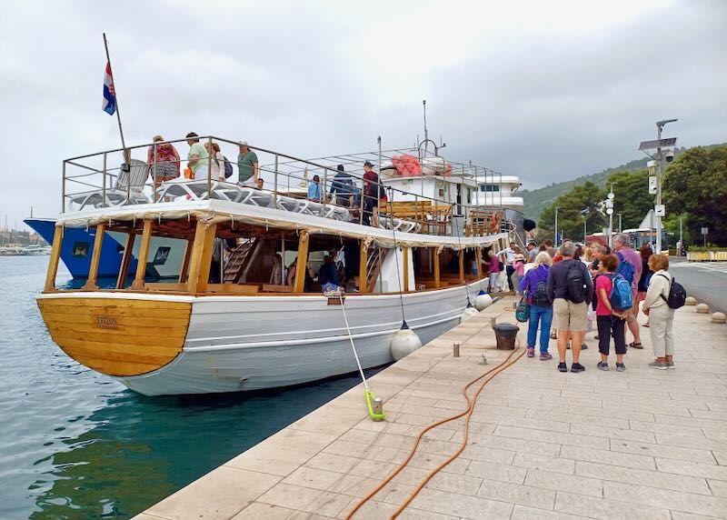 Tourist stand on the second level of a boat waiting to sail.