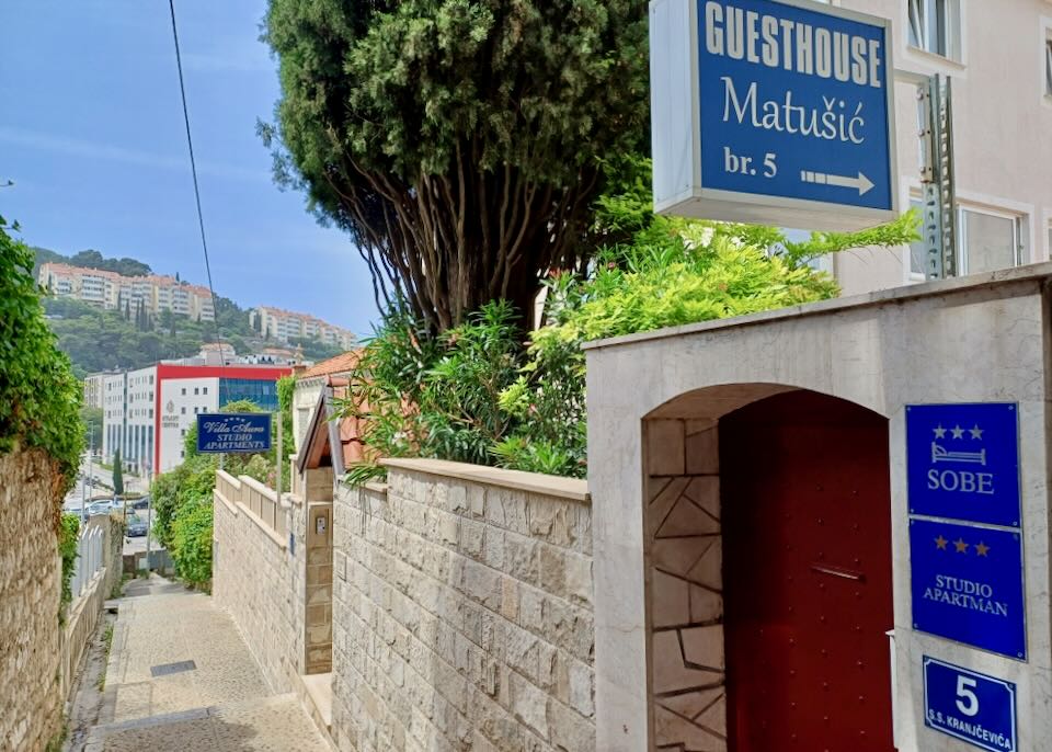 A tight sidewalk with stone walls around it leads to a guesthouse.