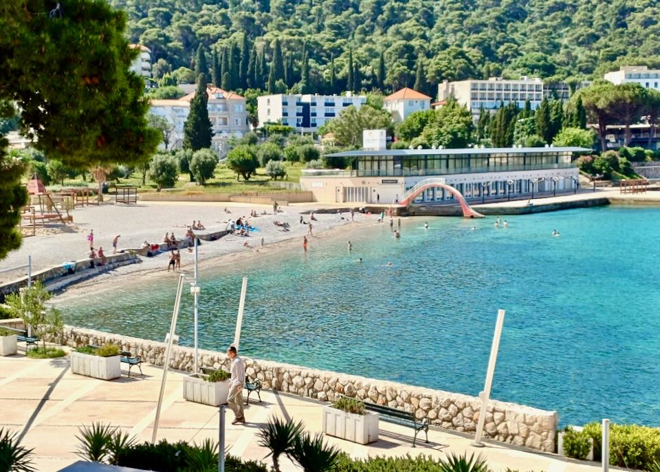 A beach with several people and clear blue water.