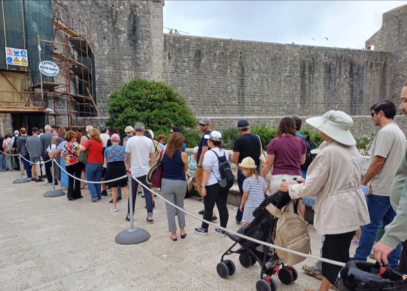 People stand in line outside a stone wall.