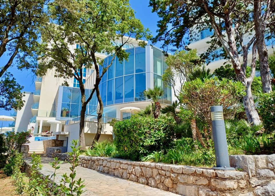 A building reflecting the blue sky sits back from a tan stone path.