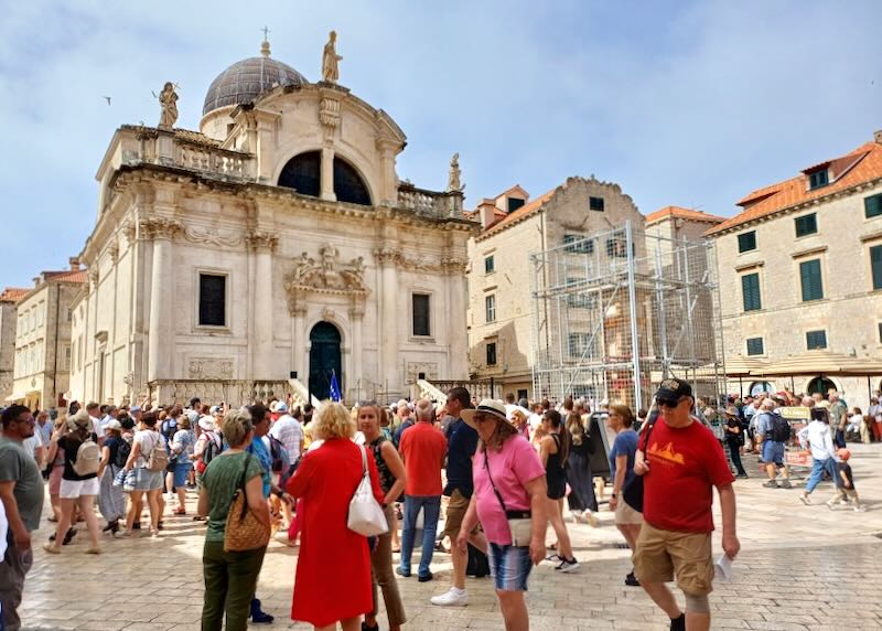 People gather around the outside of an ancient church.