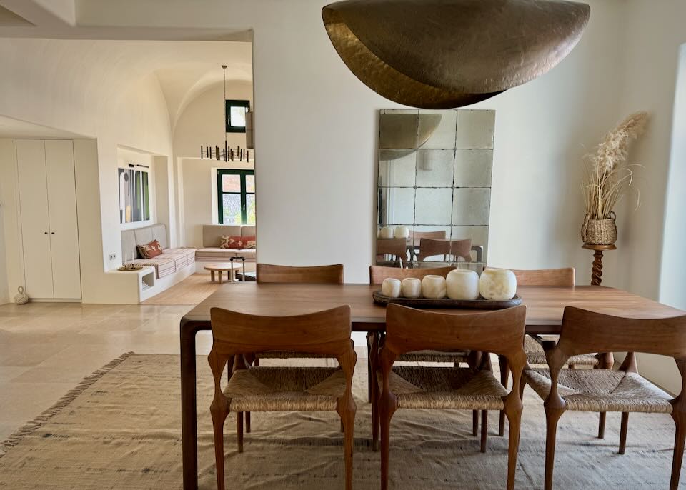 Dining room with large copper light fixture over a rustic-modern table and chairs.