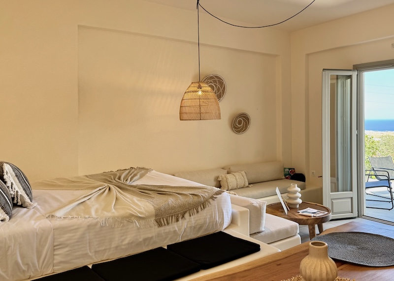 A bedroom with a sitting area and sea view at Maeva Suites in Santorini.