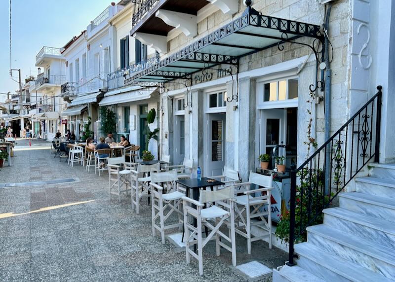 Whitewashed buildings with venetian-style balconies along a cobbled sidewalk.