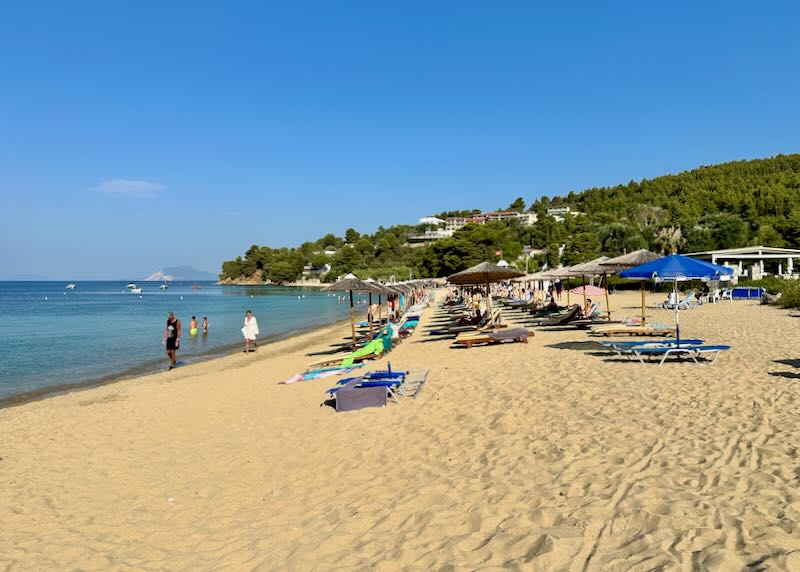 View along a wide sandy beach lined with sun umbrellas