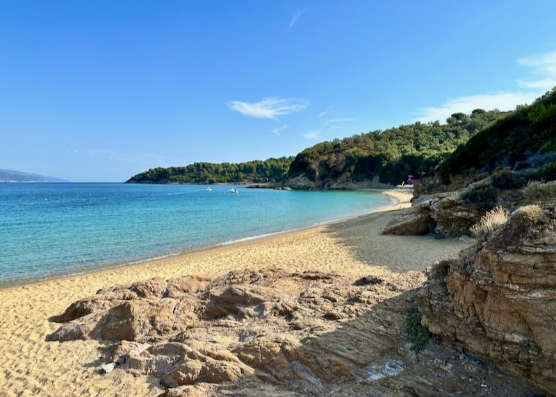 View from a rocky cove up a golden sand beach