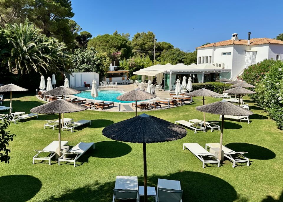 View of a hotel lawn leading to to a swimming pool.