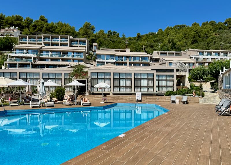 Wooden swimming pool deck with a terraced hotel rising up from behind