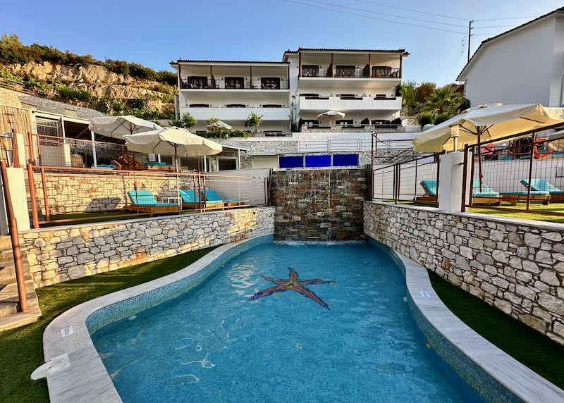 Freeform hotel swimming pool with a waterfall, flanked by terraced sun decks.