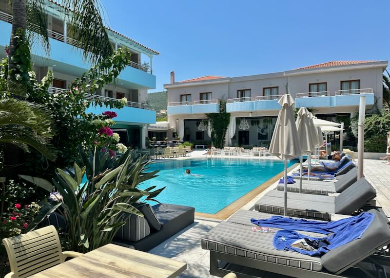 A woman swims in a hotel pool surrounded by sun beds