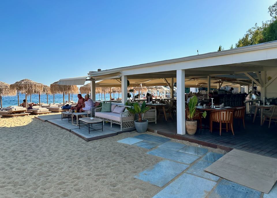 Waterside beach bar with thatched umbrella tables.