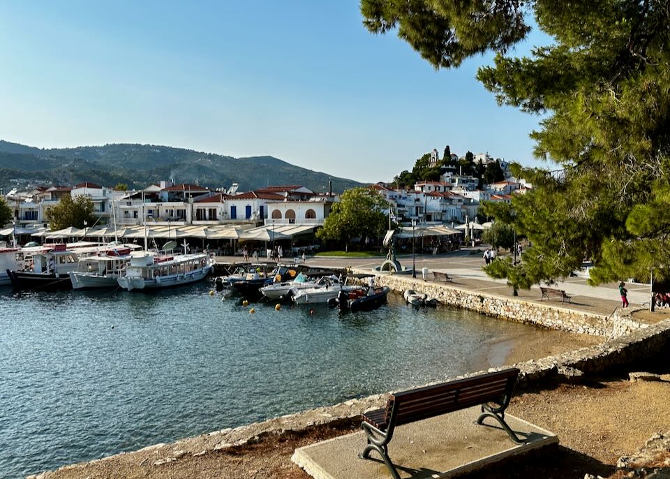 View of a small Greek harbor, lined with fishing boats and waterside restaurants.